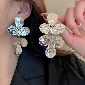 Macro detail of silver layered flower earrings with modern hammered metal texture