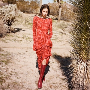 Close-up of vibrant red abstract print long sleeve maxi dress paired with tall leather boots