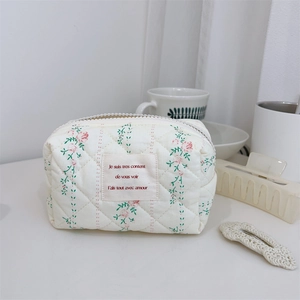 Détail d'une trousse à maquillage en coton matelassé aux motifs de fleurs pastel doux