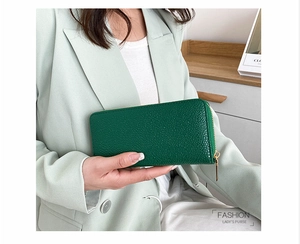Detail of dark green pebble grain leather texture on long wallet with gold zipper