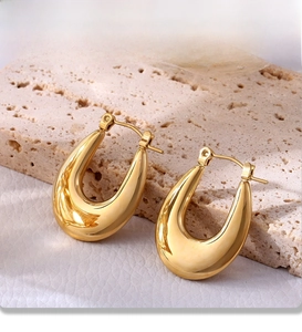 Detail view of U-shaped gold earrings with PVD plating on natural stone