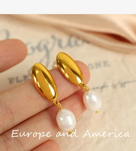 Detailed close-up of 18K gold crescent hoop earrings featuring white freshwater pearl drops