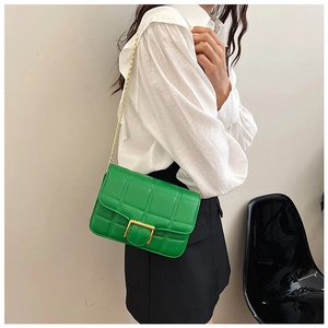 Detail view of green quilted leather bag with gold chain strap worn by a model