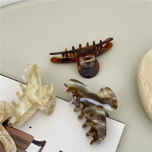Three acetate hair claws in tortoiseshell and marble patterns for elegant styling