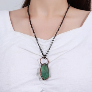 Dettaglio di collana vintage con pendente in pietra verde grezza su catena di bronzo