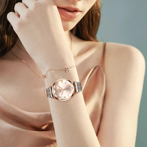 Detail of BIDEN rose gold watch with rhinestone dial worn by elegant model on silk