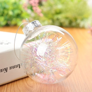 8cm clear Christmas ornament ball with iridescent tinsel on a wooden surface
