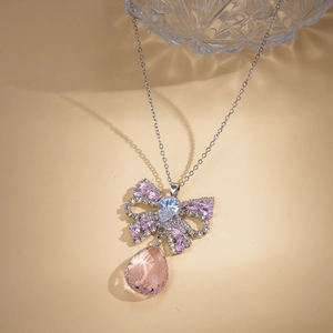 Detail of a bow-knot necklace with pink water-drop gemstone and sparkling zircons