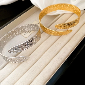 Detailed view of hollow vine patterns on gold and silver vintage style open bangles