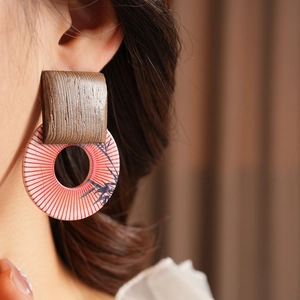Close-up of geometric wood and resin printed earring worn on a model with natural lighting