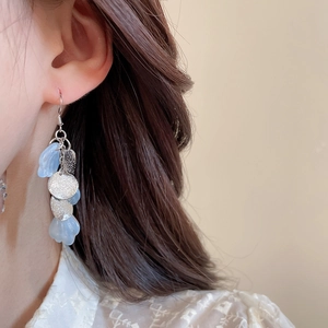 Macro shot of light blue acrylic petal drop earrings worn on a model with lace details