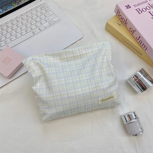 Detailed close-up of blue-green checkered makeup bag with woven fabric texture and label