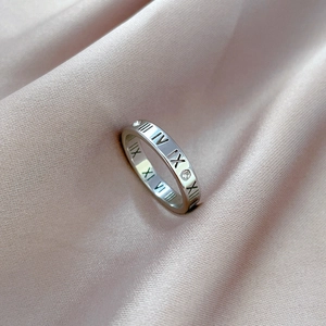 Detail of silver titanium ring with Roman numerals and embedded zircon on pink silk