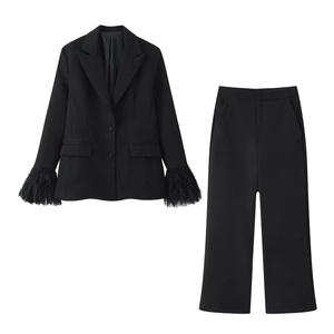 Detalle de los puños con plumas en un conjunto de traje negro de chaqueta y pantalón