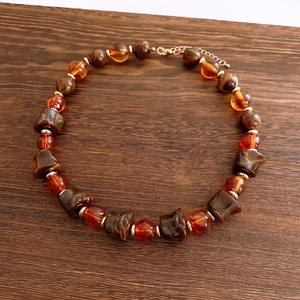 Close-up of vintage amber geometric beads and gold chain on dark wood background