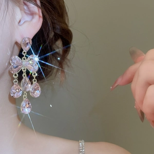 Gros plan détaillé de boucles d'oreilles nœud rose avec glands en zircon et gemmes goutte d'eau