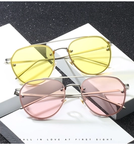 Close-up of yellow and pink ocean lens sunglasses with silver metal frames on white blocks