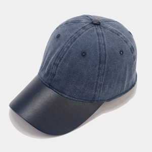 Vintage navy blue denim baseball cap with textured leather brim shown from a 45-degree angle
