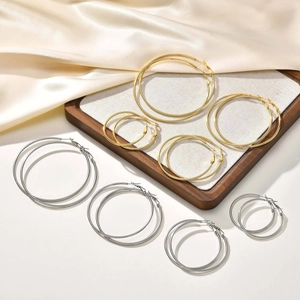 Macro detail of various sizes hoop earrings in gold and silver on silk background