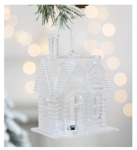 Maison de Noël transparente lumineuse sur branches de pin enneigées avec bokeh chaleureux