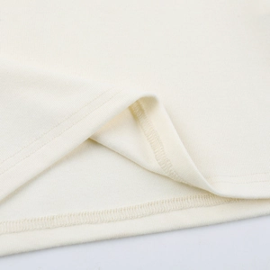 Close-up of cream ribbed fabric showing double-stitched seams and lace edge detail