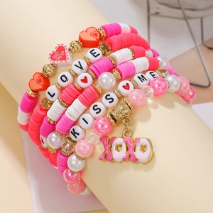 Close-up of bohemian heart charm bracelets with red and pink Heishi beads and XOXO pendant