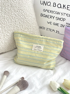 Detail of blue striped canvas makeup bag with white label on warm cozy background