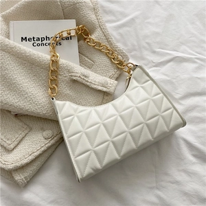 Detail der weißen gesteppten Handtasche mit goldener Kette auf Tweed-Jacke und Buch