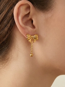 Close-up of golden bow tassel earrings on a model showing fine jewelry details