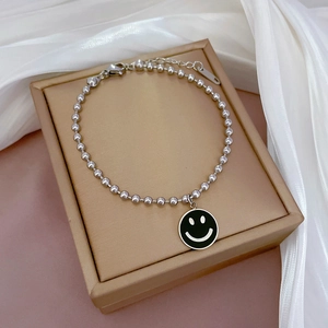 Nahaufnahme der Silberperlen-Armband mit schwarzem Emaille-Smiley auf einer Schmuckbox