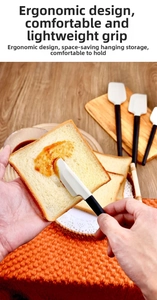 Close-up of silicone spatula with beech wood handle spreading cream on bread slices