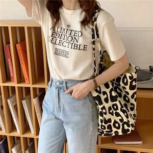 Detail of a large leopard print canvas tote bag styled with a white graphic tee and jeans