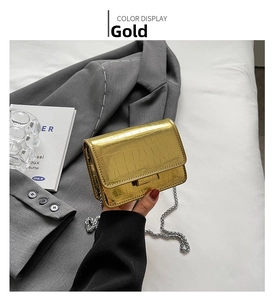 Detail shot of golden crocodile textured mini bag with elegant metallic chain strap