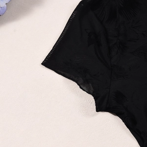 Dettaglio del tessuto in rete nera trasparente con motivi jacquard su abito a due pezzi