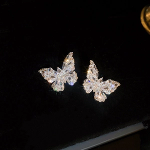 Macro shot of silver butterfly stud earrings with sparkling cubic zirconia on black velvet