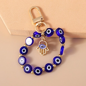 Detail of blue Evil Eye beads and golden Hand of Fatima pendant on a keychain