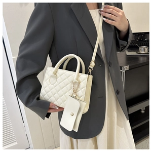 Detailed view of white quilted handbag with matching coin purse on a stylish model