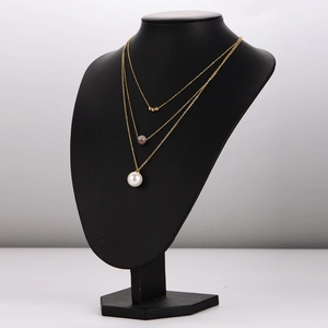 Collier doré à trois rangs avec pierre rose et perle blanche sur mannequin noir