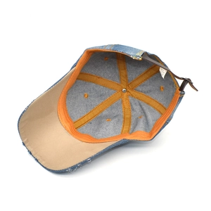 Detail of distressed blue denim baseball cap interior showing 100% cotton label and leather strap