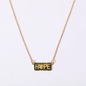 Detail view of golden necklace pendant with green stones and HOPE engraving