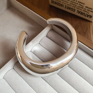 Macro shot of silver wide open cuff bracelet on grey velvet tray with modern glossy finish