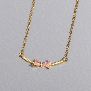 Detailed macro view of gold bow necklace with pink triangular zircons and micro pave stones