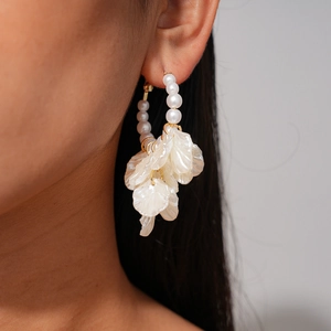 Close-up of elegant pearl flower petal drop earrings worn on ear with crystal accents