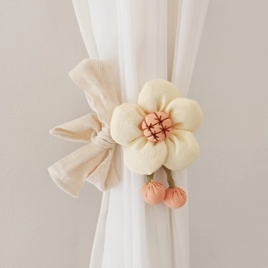 Detail of beige fabric flower curtain tieback with embroidery and small pink pendants