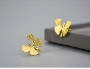 Macro shot of gold ginkgo leaf stud earrings showing brushed metal texture details