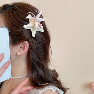 Detail of starfish hair clip with fabric flower and beads on model side profile