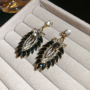 Dettaglio macro di orecchini vintage a goccia con placcatura in oro e foglie smaltate nere
