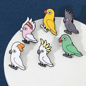 Gros plan détaillé de six broches perroquets colorées en émail sur un plateau blanc