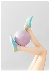 Dettaglio dei gommini in silicone antiscivolo e cinghie incrociate su calze yoga sfumate