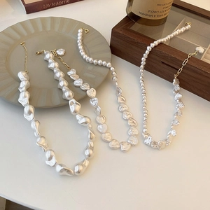 Detail of baroque pearl heart necklaces on a ceramic plate and wooden jewelry box